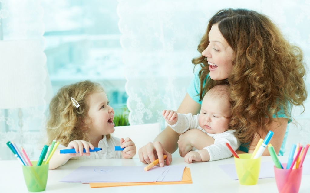 Beautiful mother and her children drawing at home