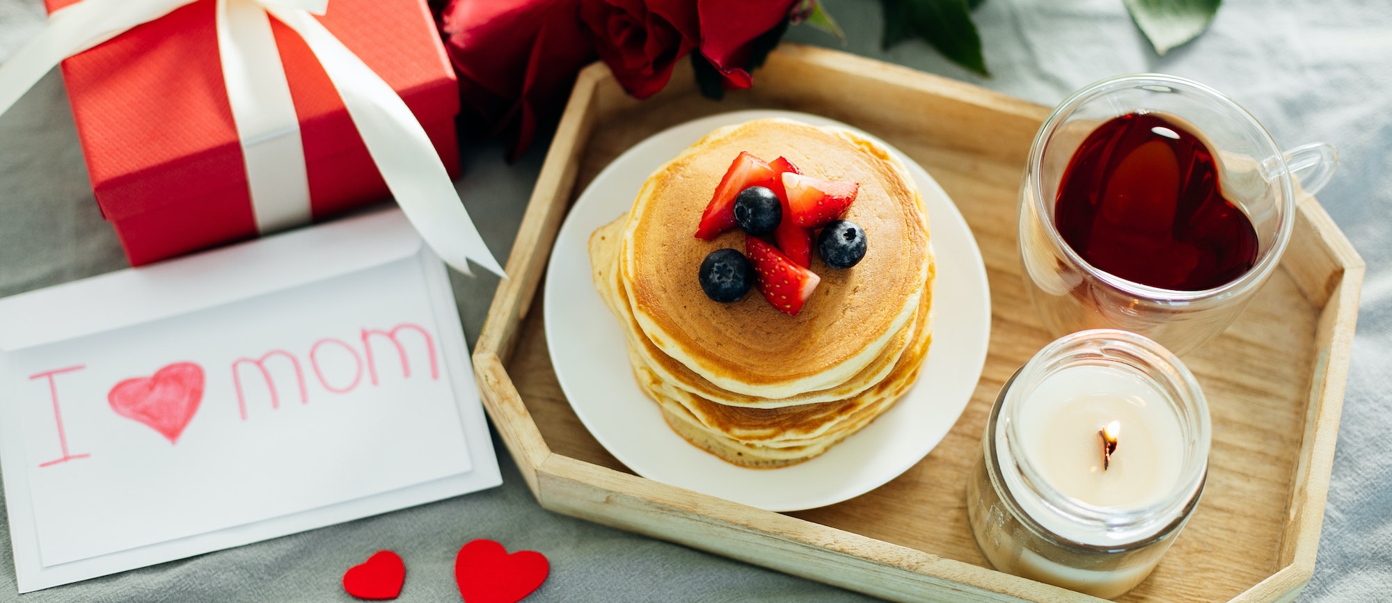 Banner image for desing web page. Mother's Day concept. Pancakes with berry, tea cup, burning candle